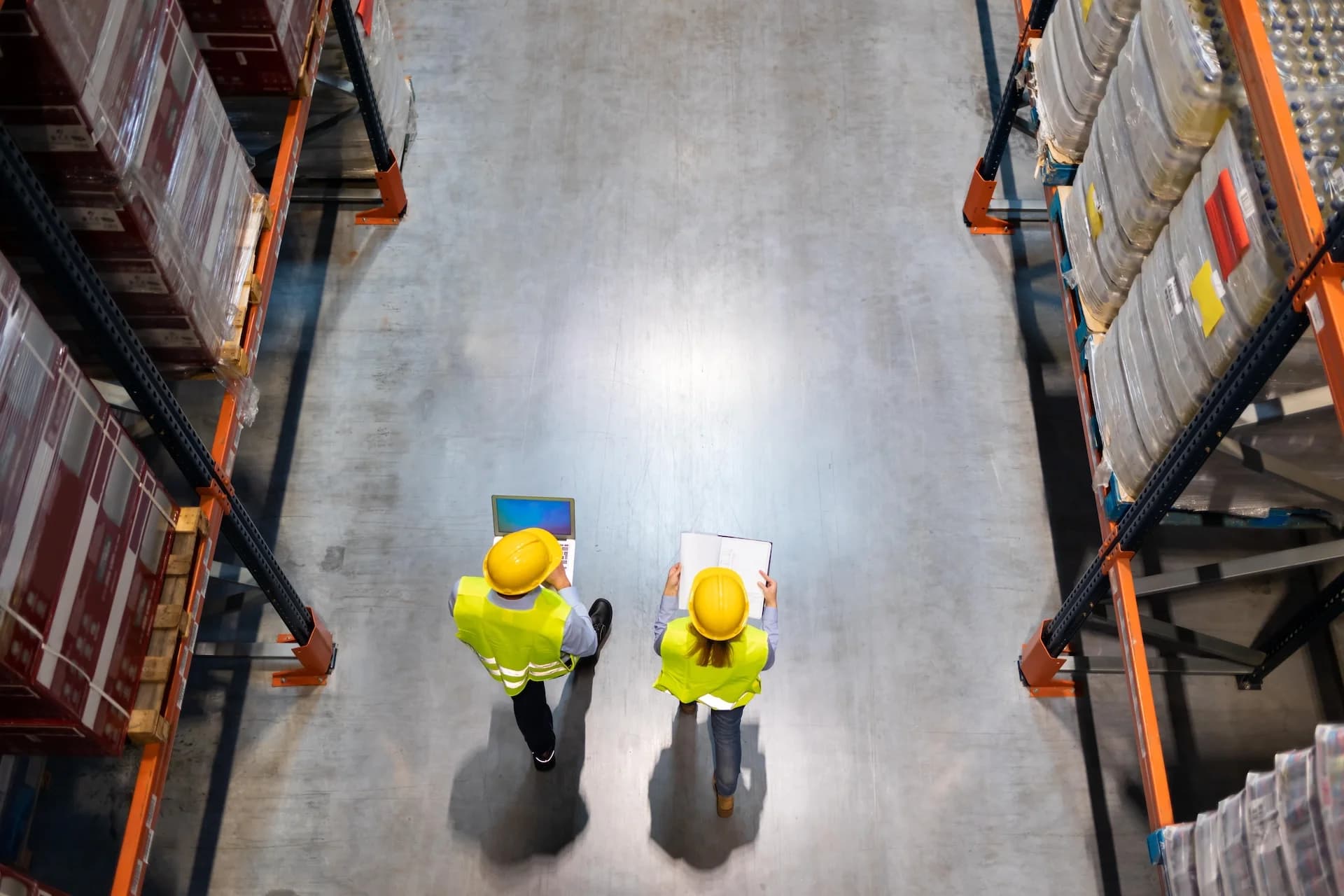 a man and a woman in safety gear walking around an warehouse