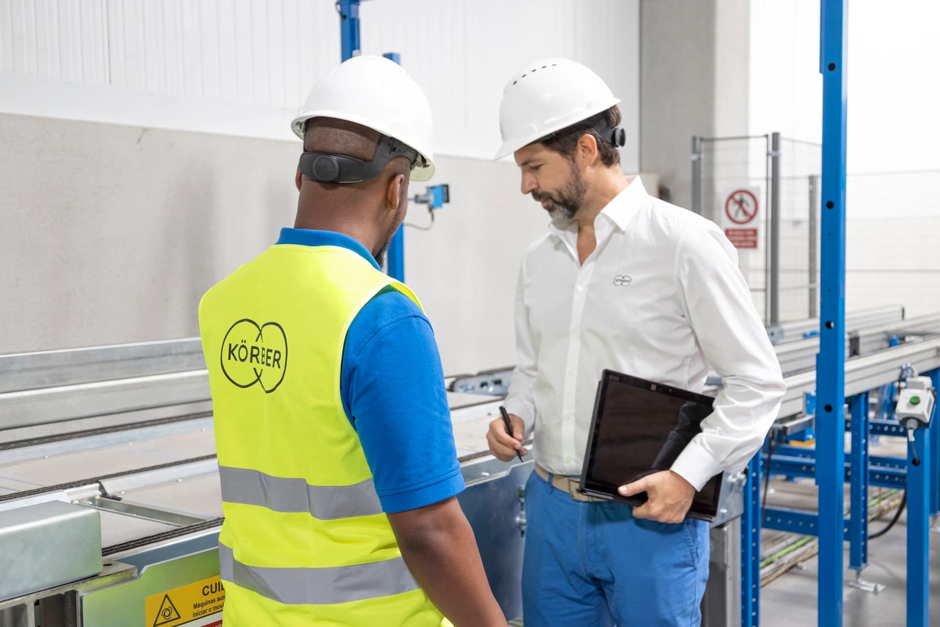 zwei Körber-Mitarbeiter mit Schutzhelmen in einem Lager