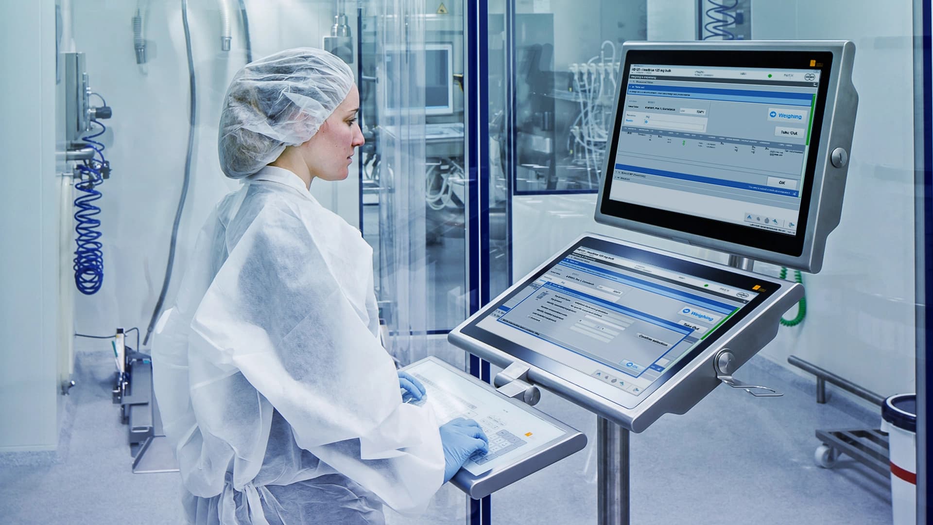 A woman in a lab coat is focused on using a computer in a laboratory setting.