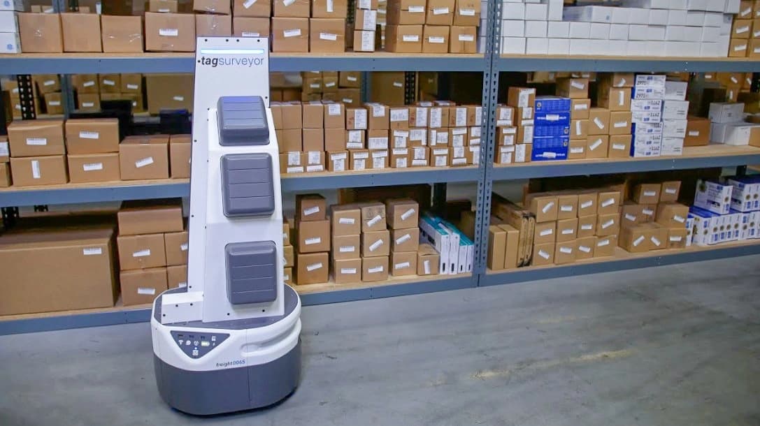 A robot navigates a warehouse filled with stacked boxes and shelves, showcasing an automated storage environment.