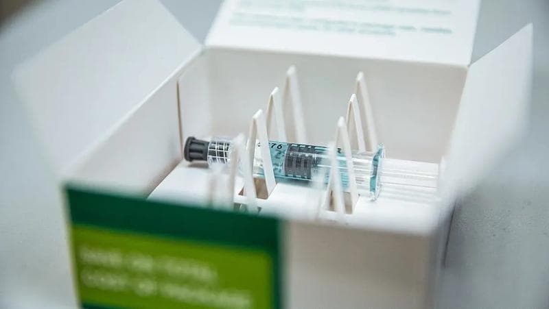 Eine Schachtel mit einer Spritze und einer Nadel, die die innovativen pharmazeutischen Verpackungsstandards von Körber demonstriert.