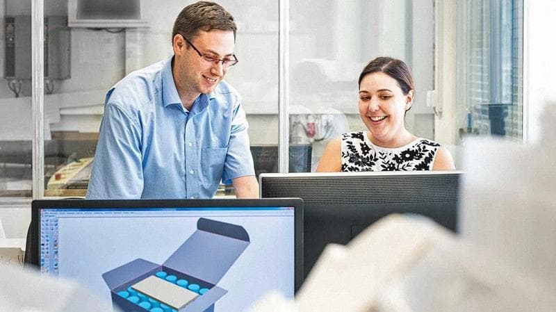 Man and woman looking at a computer screen, laughing.