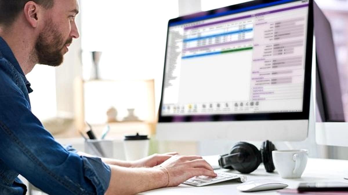 Man typing on a computer, looking at a screen with data and graphics.