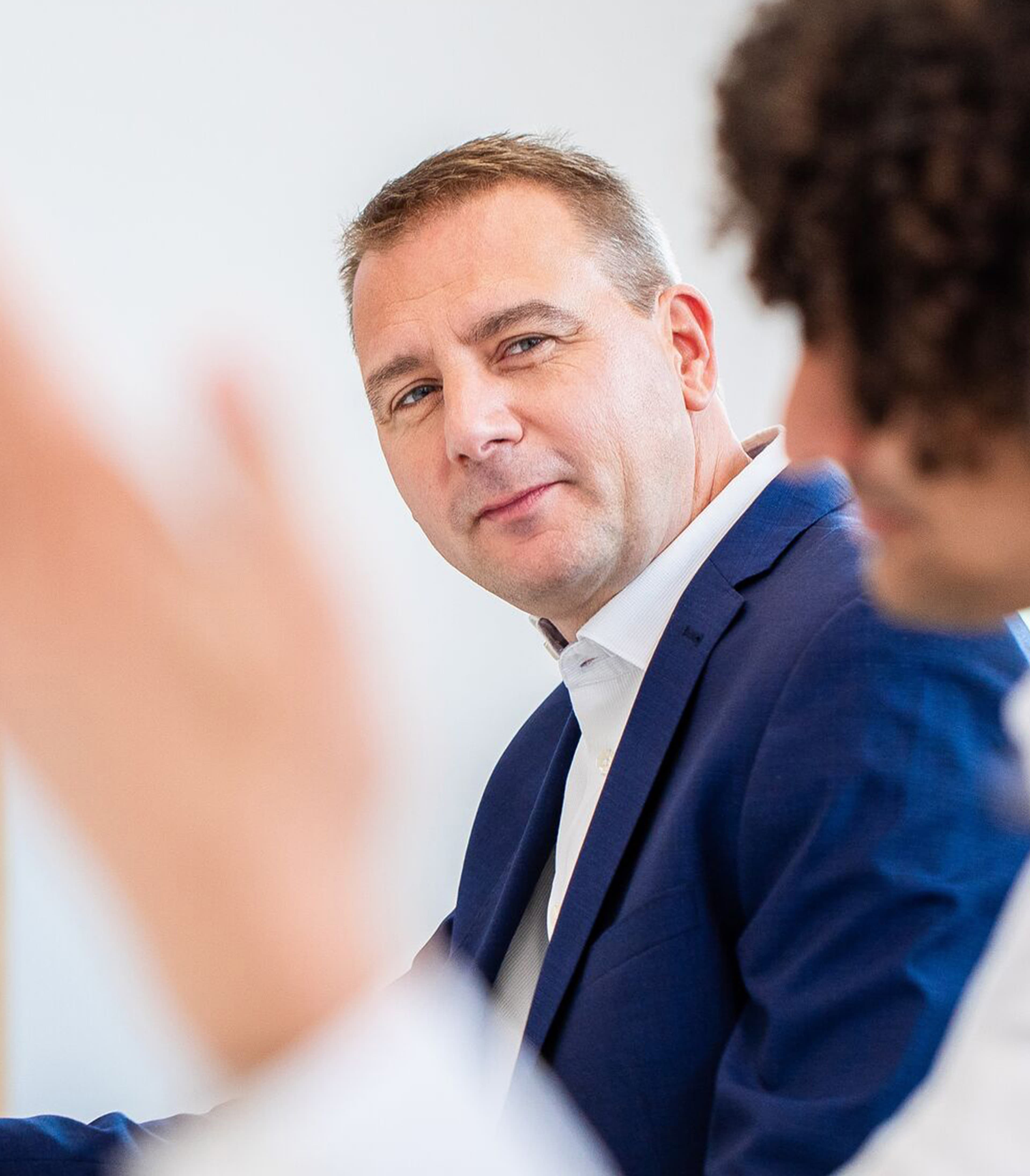 Man wearing a blue suit looking at a person out of focus