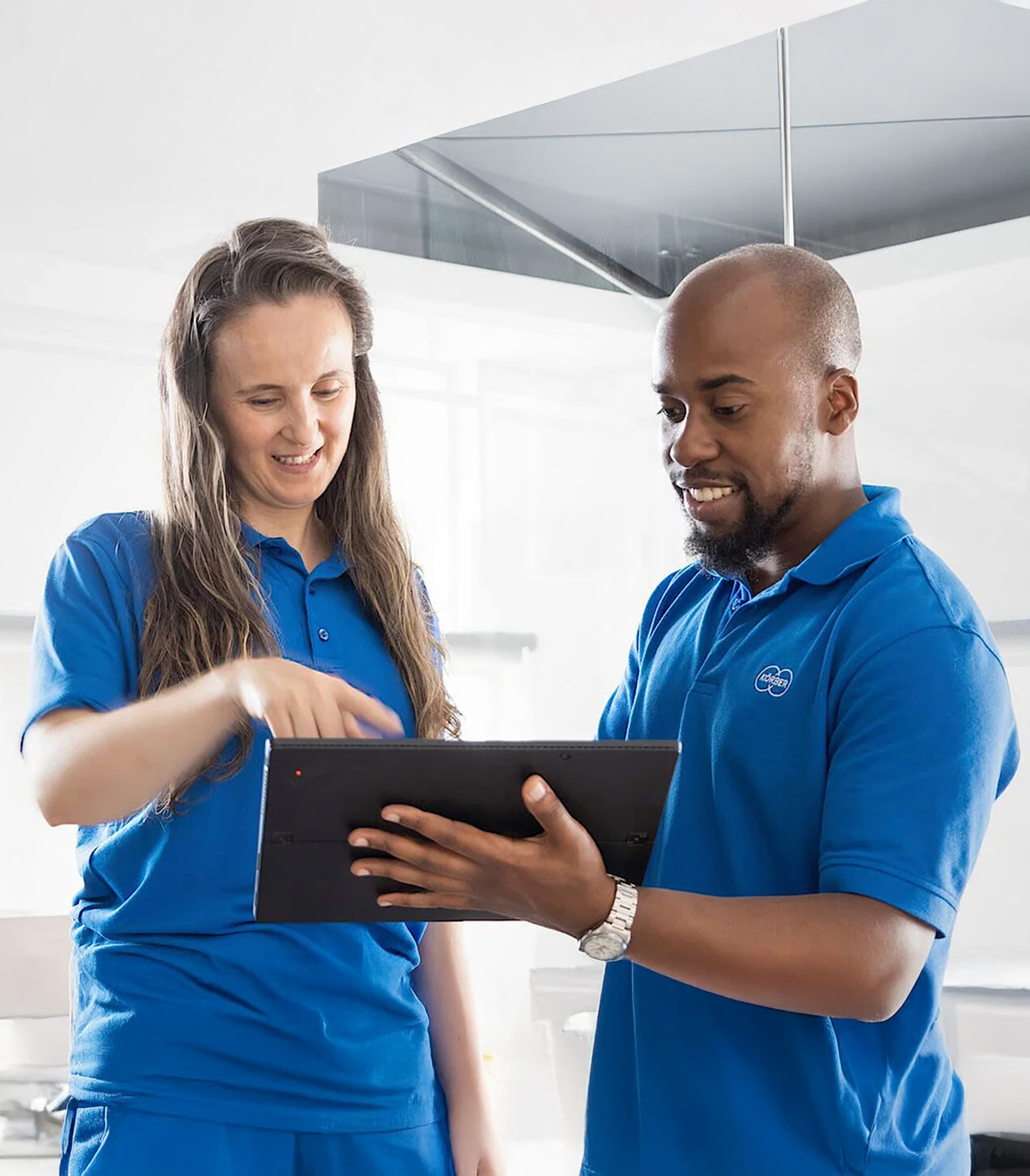 Two Körber employees looking at a tablet device
