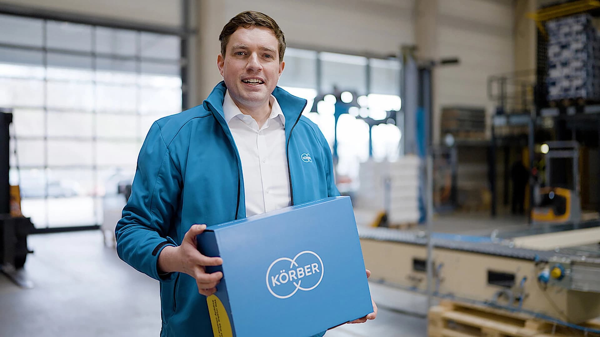 Körber-Mitarbeiter mit einer blauen Verpackung mit dem Körber-Logo.