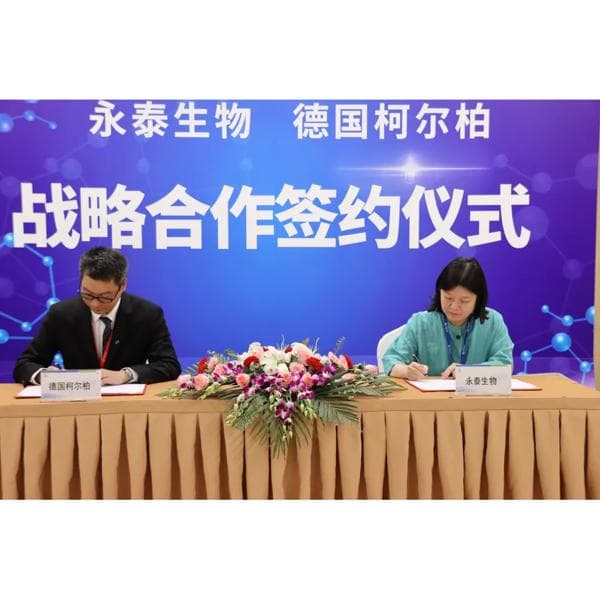 Twos representatives from Immunotech Biopharm signing the agreement with Körber on a table with flowers and chinese characters on the background.