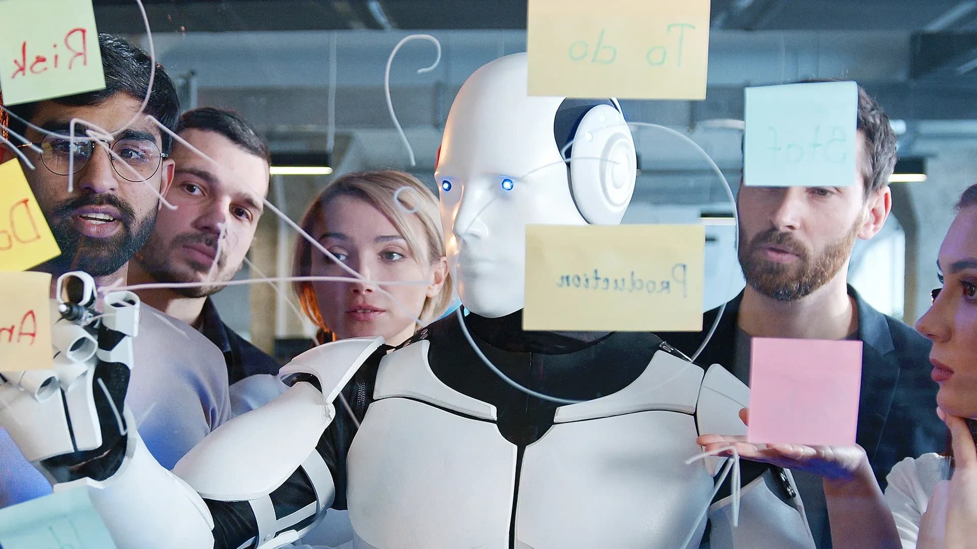 Robot writing on a board while humans watch.