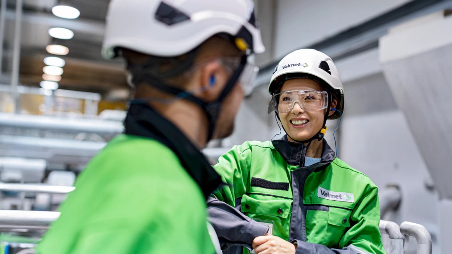 Zwei Personen von Valmet in grün-weißer Sicherheitskleidung unterhalten sich.