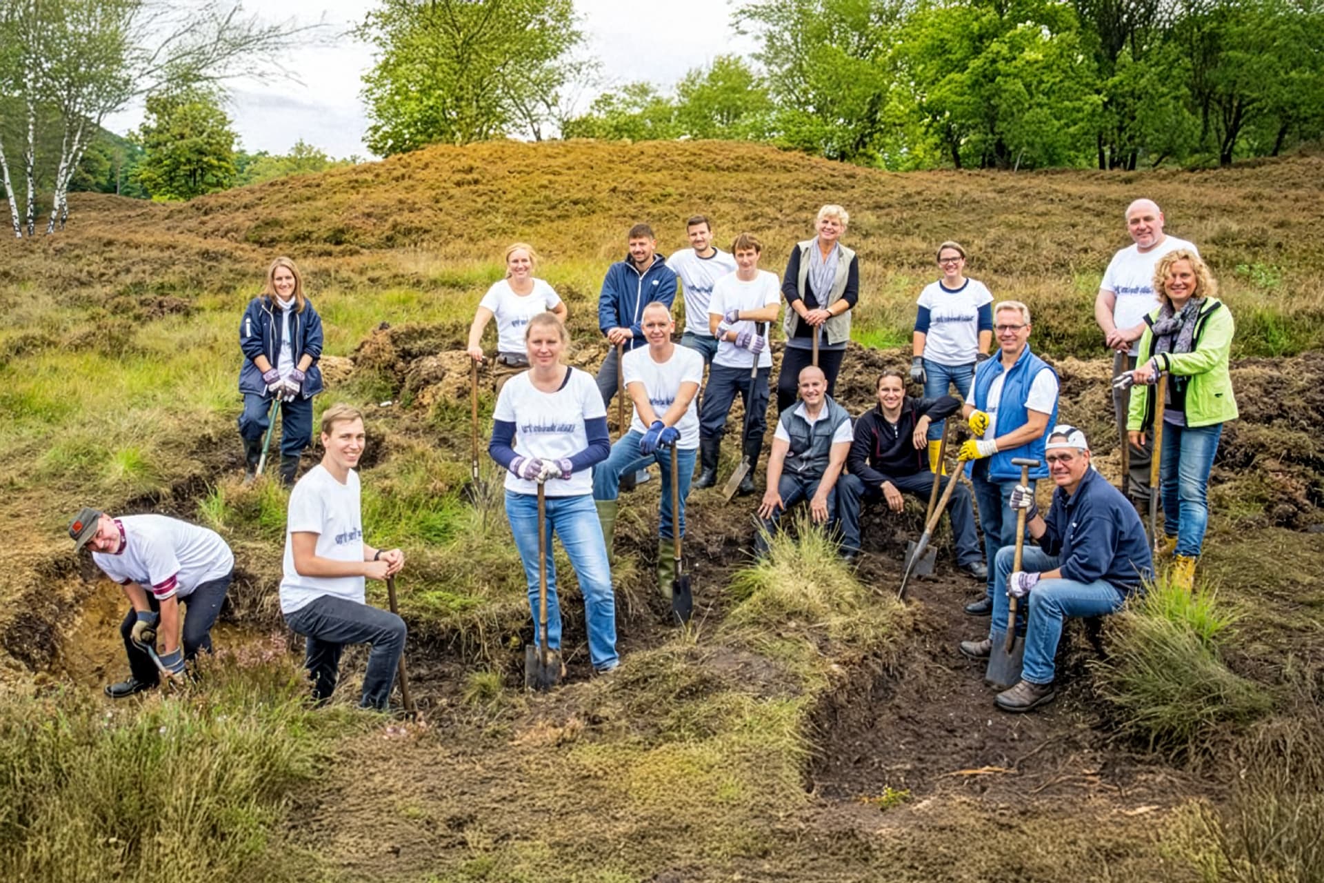 A diverse group of people poses in a field after planting trees