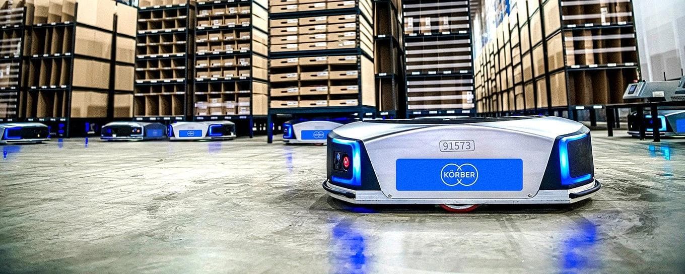 Ein Lagerhaus mit mehreren Autonomen Mobilen Robotern (AMRs), die sich effizient durch den Raum bewegen.
