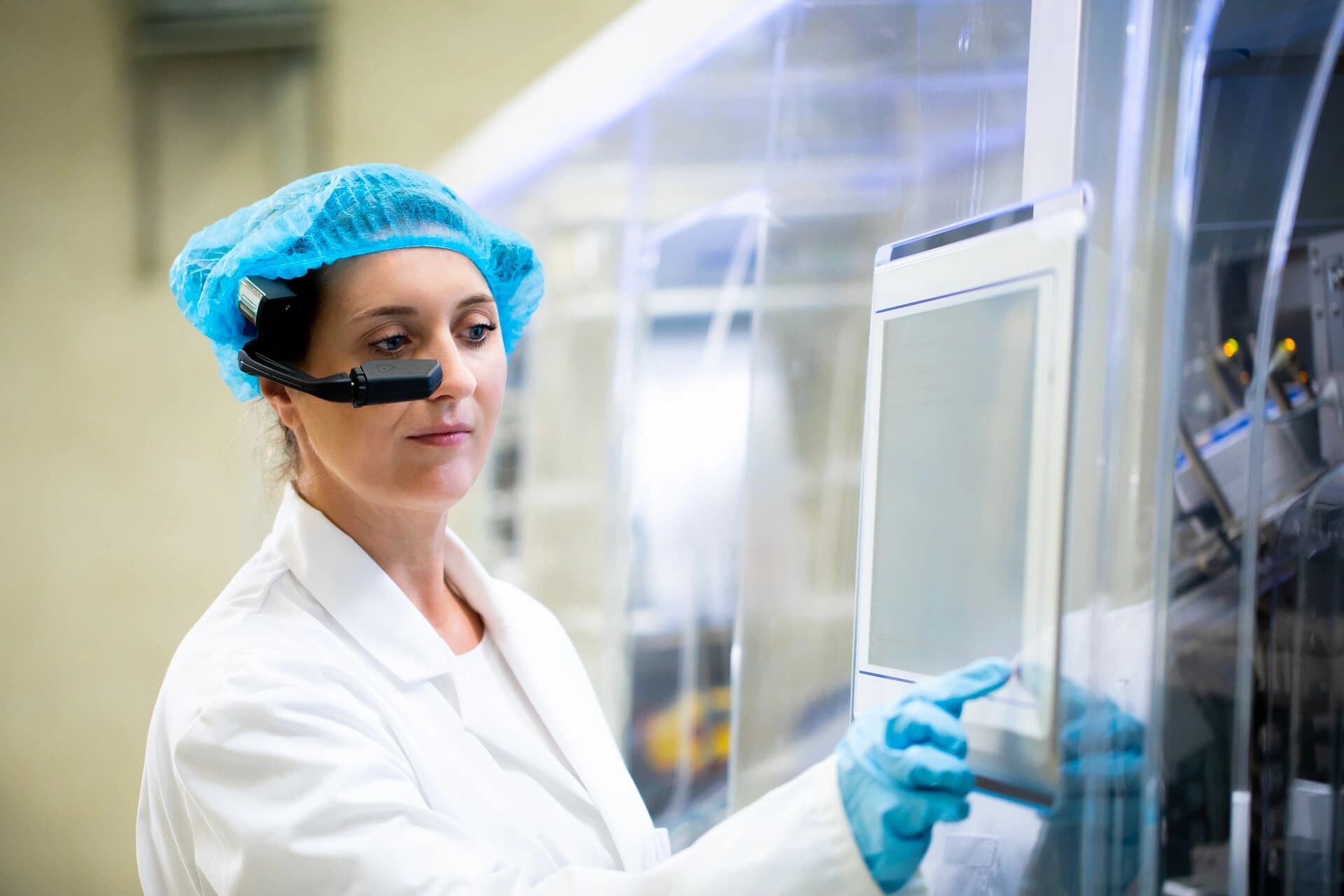 A woman in a lab coat examines data on a computer screen in a laboratory setting.
