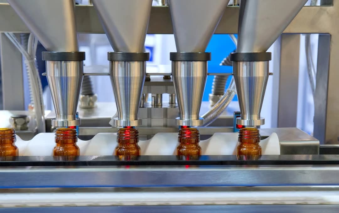 Eine Flüssigkeitsabfüllmaschine ist in Betrieb und füllt Flüssigkeit in Flaschen auf einer Produktionslinie ab.