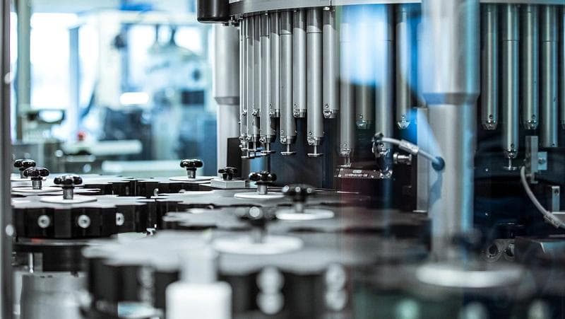Detailaufnahme einer Inspektionsmaschine von Körber Pharma, die Flaschen in einer Fabrikumgebung produziert.