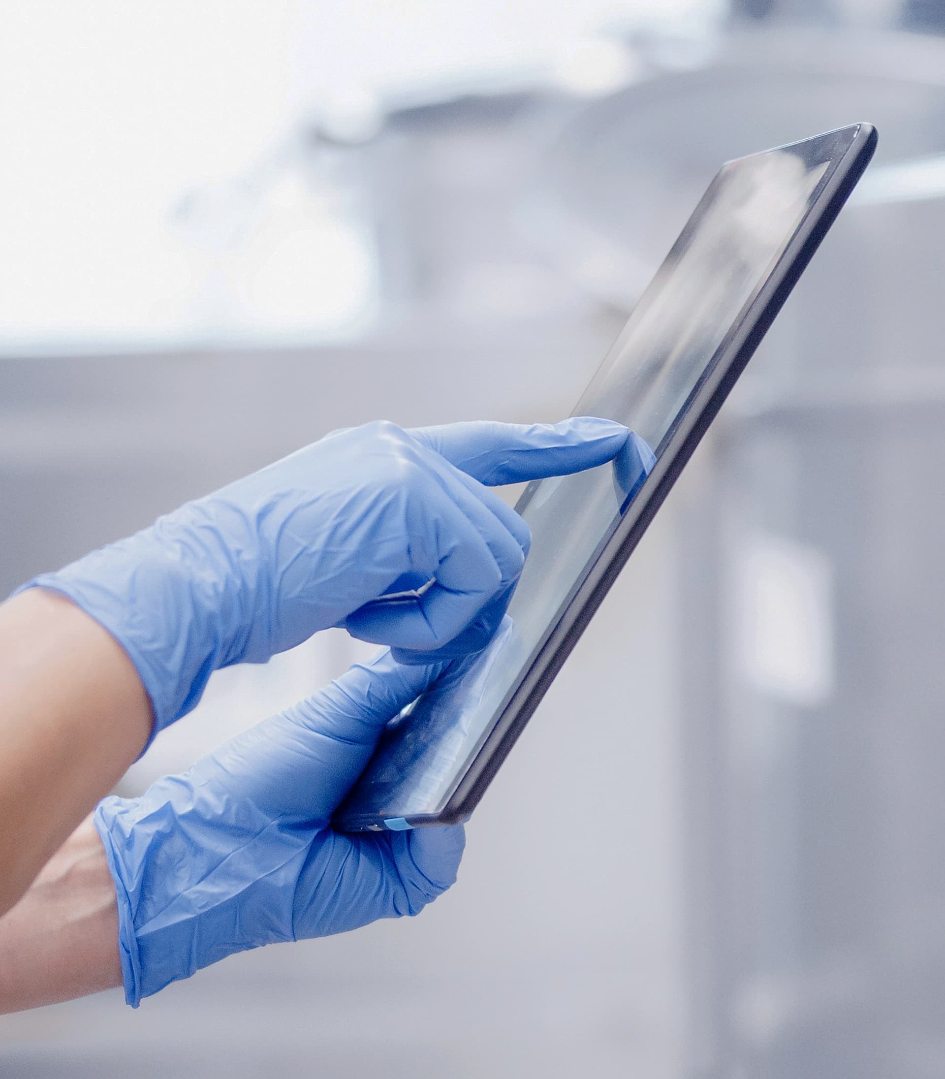 Hands with blue gloves touch the screen on a tablet.