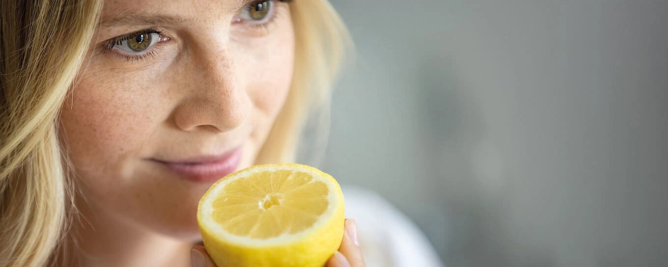 Woman smelling a lemon with a happy face.