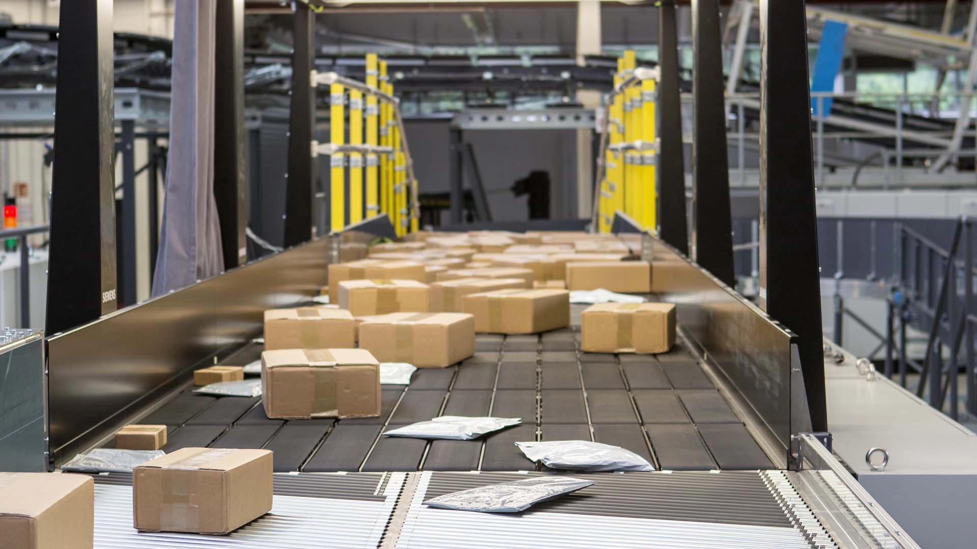 Das Förderband von Siemens Logistics transportiert Kartons und veranschaulicht effiziente Logistikabläufe.