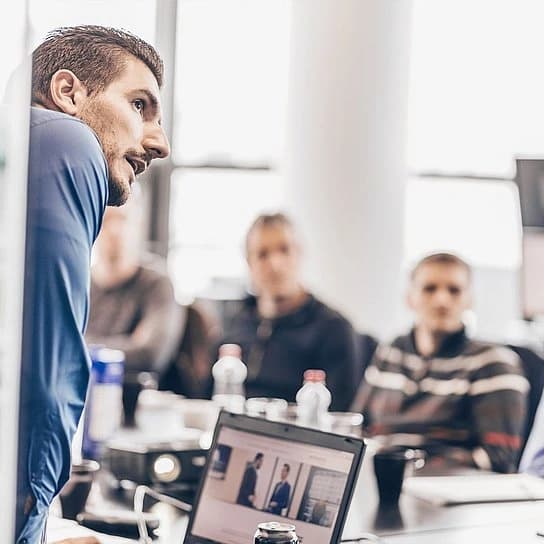 Menschen in einem Workshop, mit einem Mann als Moderator.