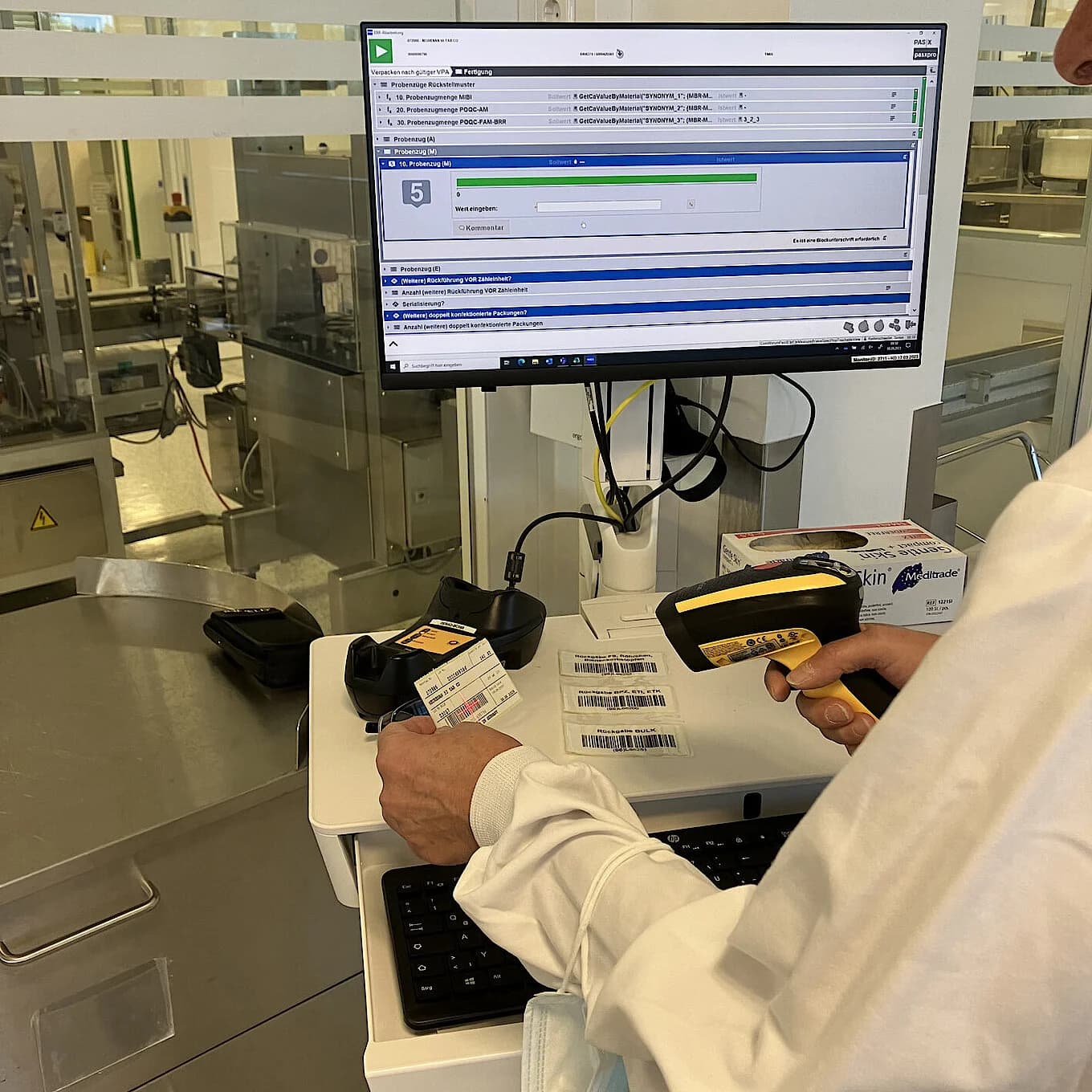 Employee scanning packaging labels at a workstation using PAS-X MES to digitalize and verify production data.