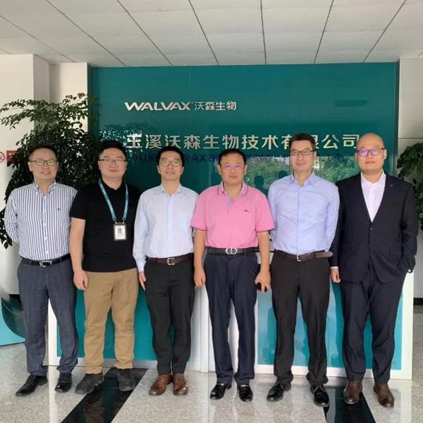 Walvax Biotechnology team standing in front of a background with chinese characters.