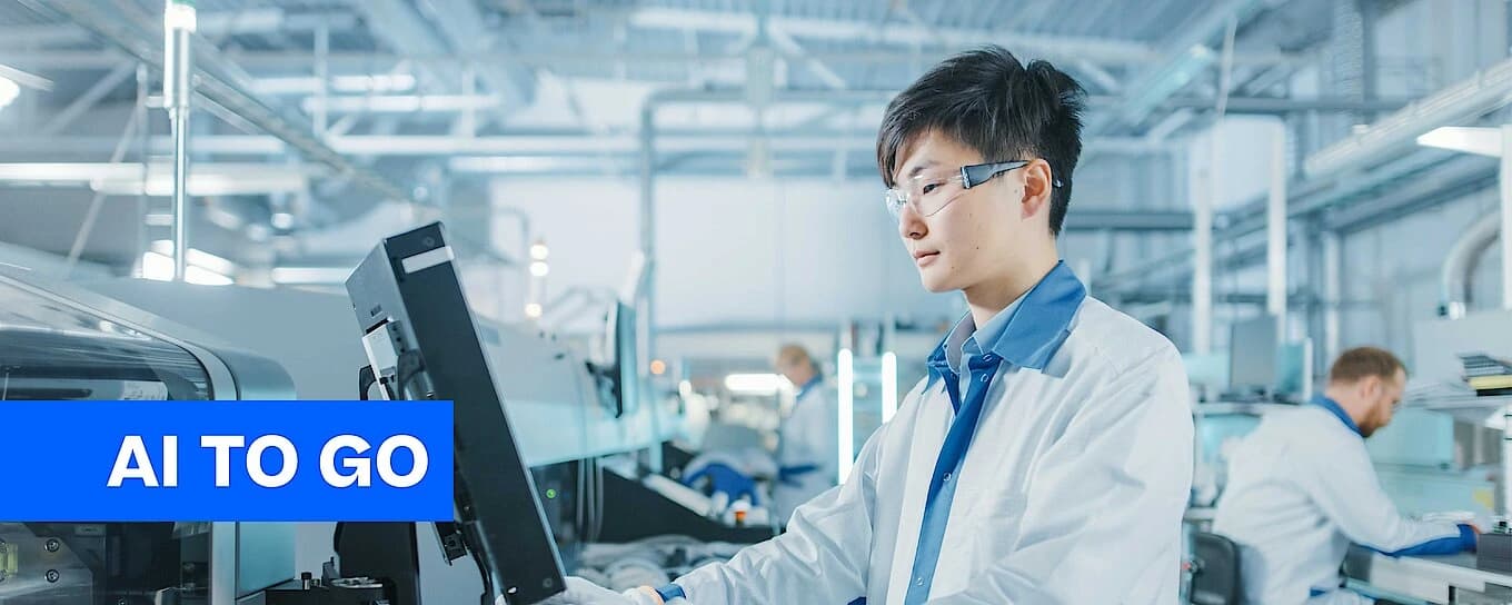 A man in a lab coat is focused on his work while using a computer in a laboratory setting.