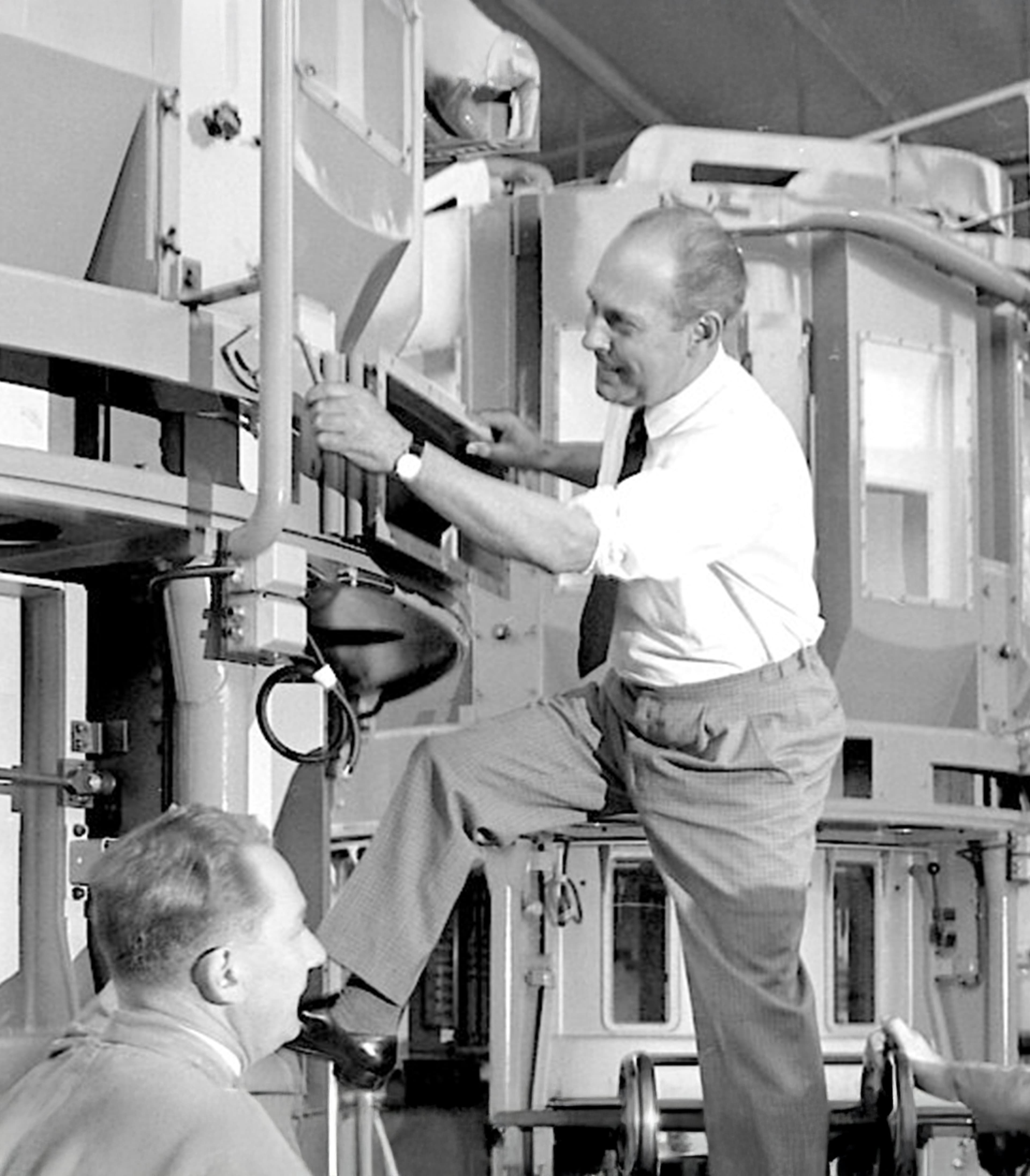 Black and white photo of two men next to a machine