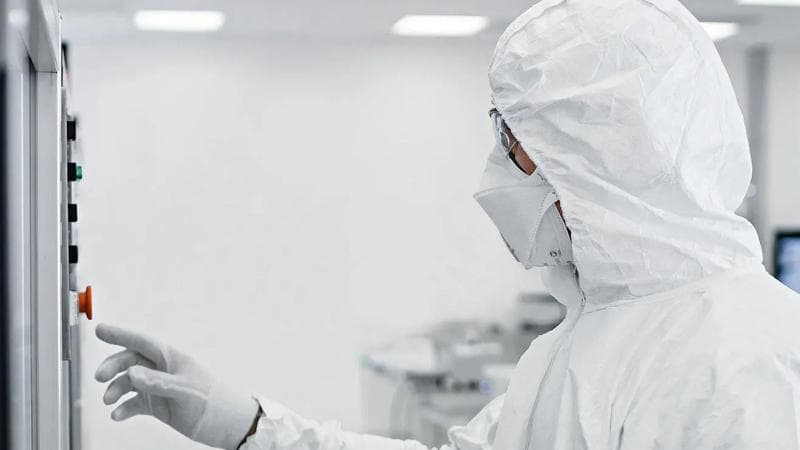 Eine Person in Schutzkleidung bei der Arbeit an einer pharmazeutischen Maschine.