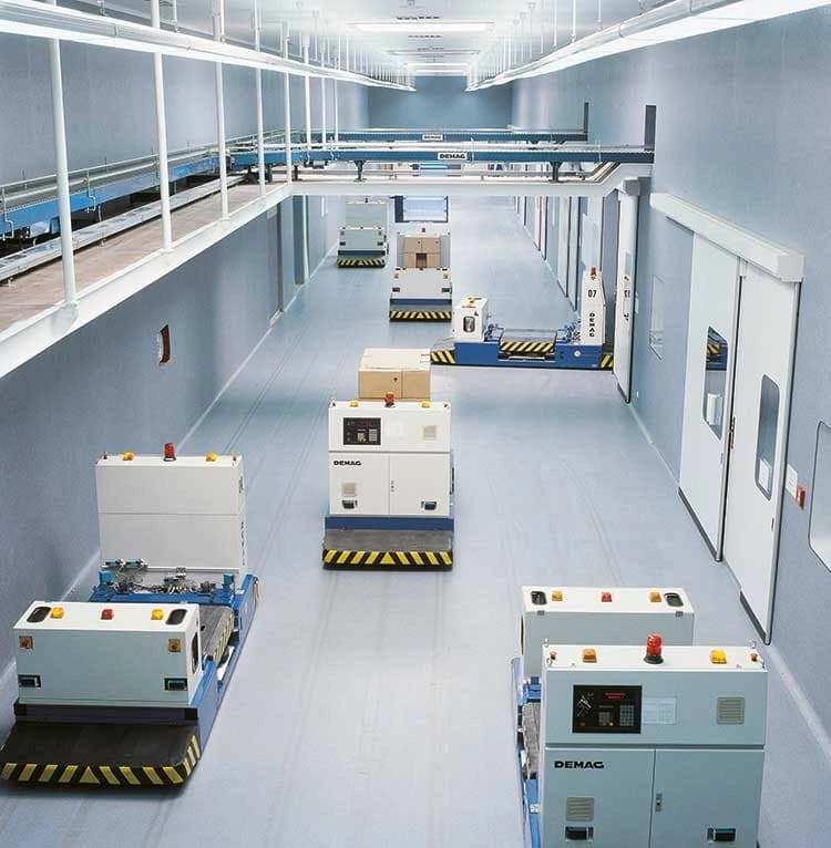Automated guided vehicles transporting materials inside a clean, high-tech pharmaceutical facility.