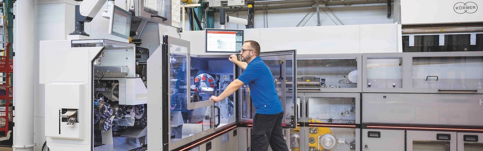 A man operates a machine in a factory, focused on his task amidst industrial surroundings.