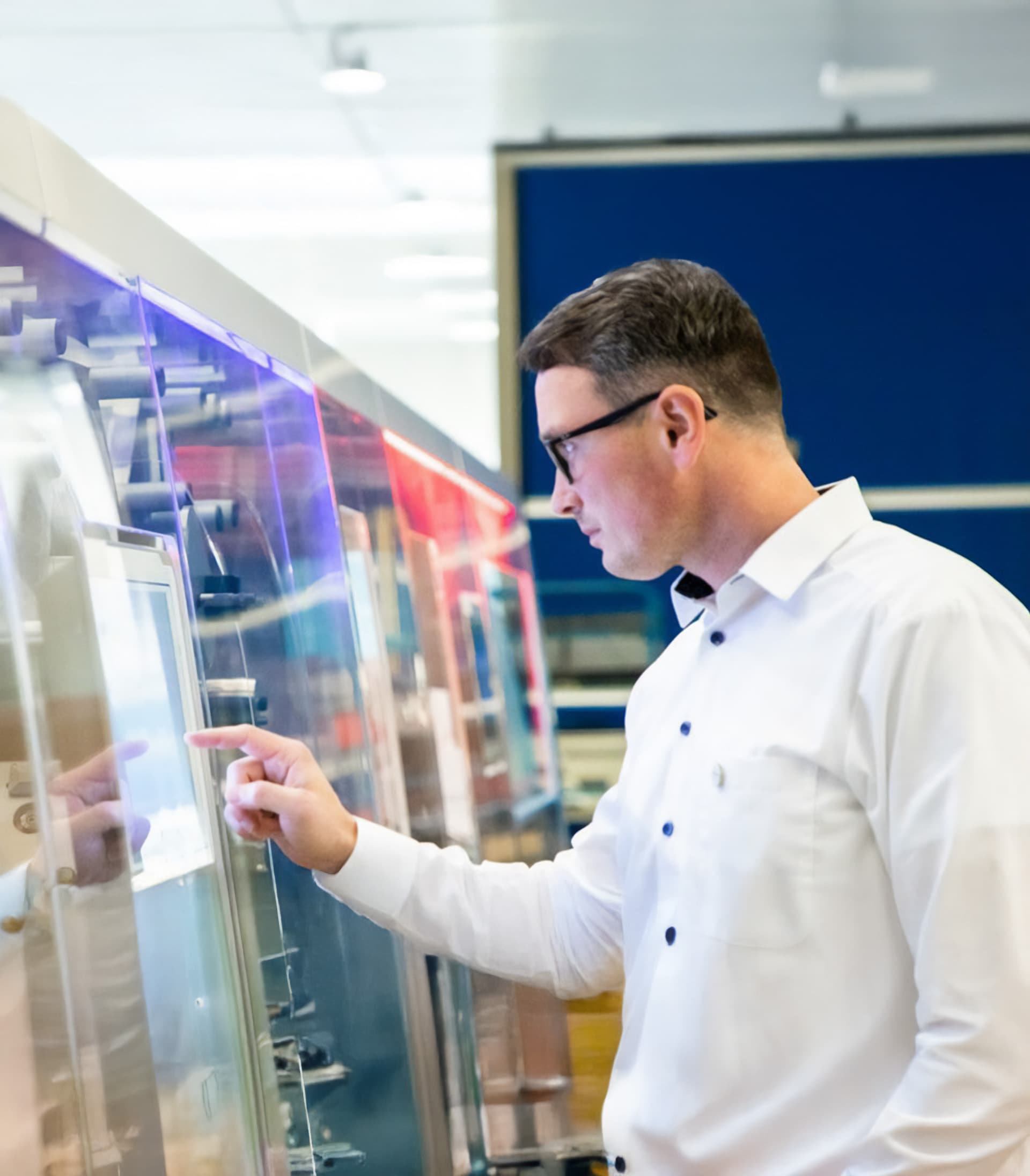 Ein Koerber-Mitarbeiter bei der Bedienung einer Touchscreen-Oberfläche an einer Industriemaschine.