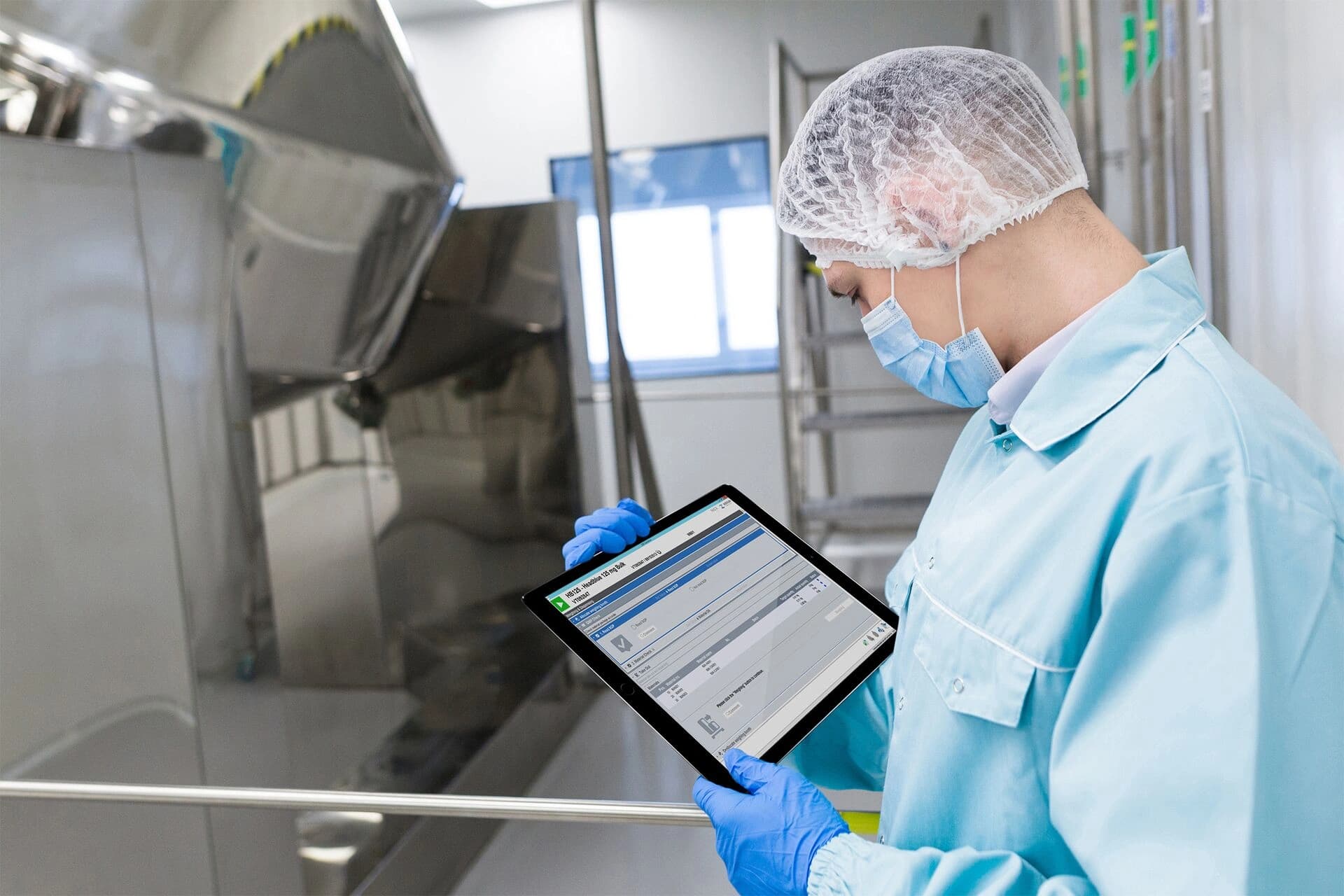 Ein Mann im Laborkittel hält ein Tablet und wirkt konzentriert und engagiert bei seiner Arbeit.