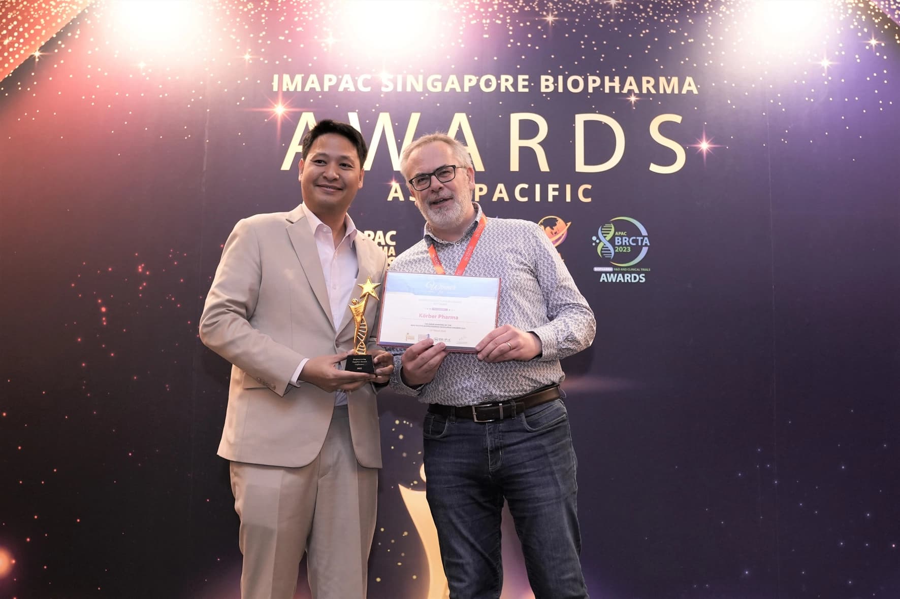Two men stand with a bioprocessing award in front of a wall, showcasing their recognition in Asia's awards event.