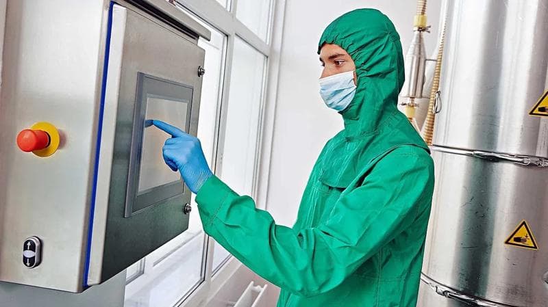 Asiatischer Pharma-Mitarbeiter in einem Schutzanzug.