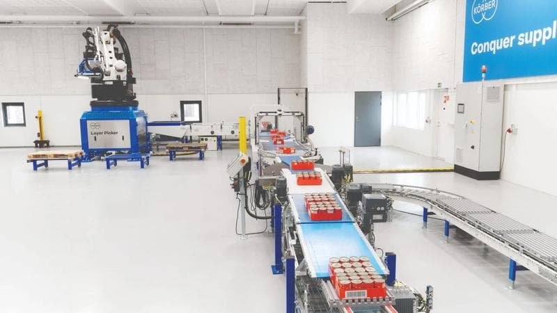 A factory scene with a conveyor belt and layer picker, highlighting modern warehouse automation solutions.