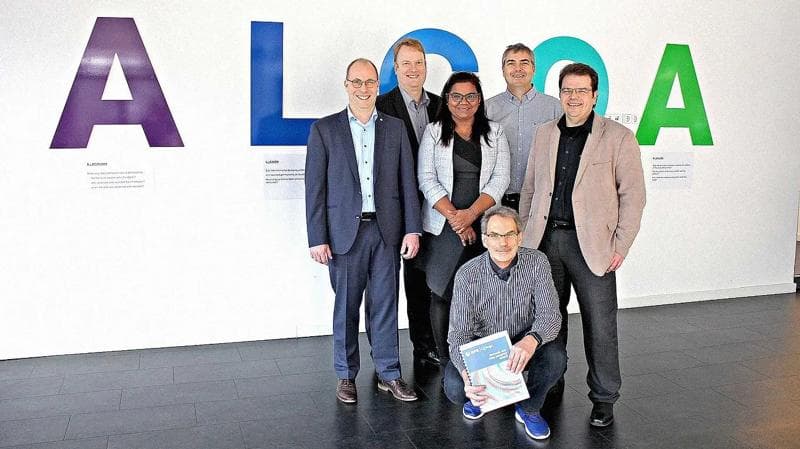 6 Körber-Mitarbeiter stehen vor einem ALCOA+-Hintergrund.