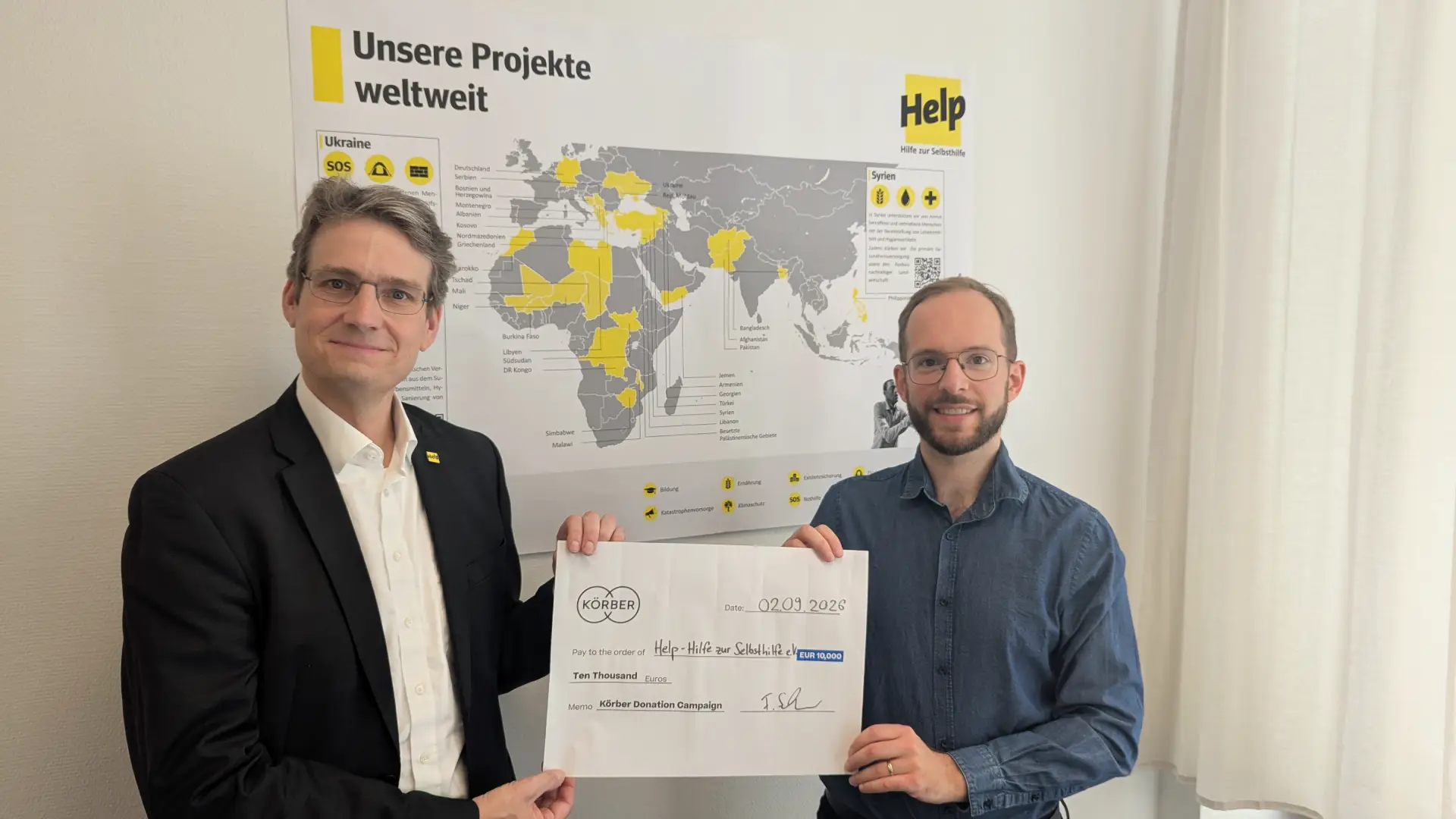 Two Körber employees holding the 80.000€ check for donation.