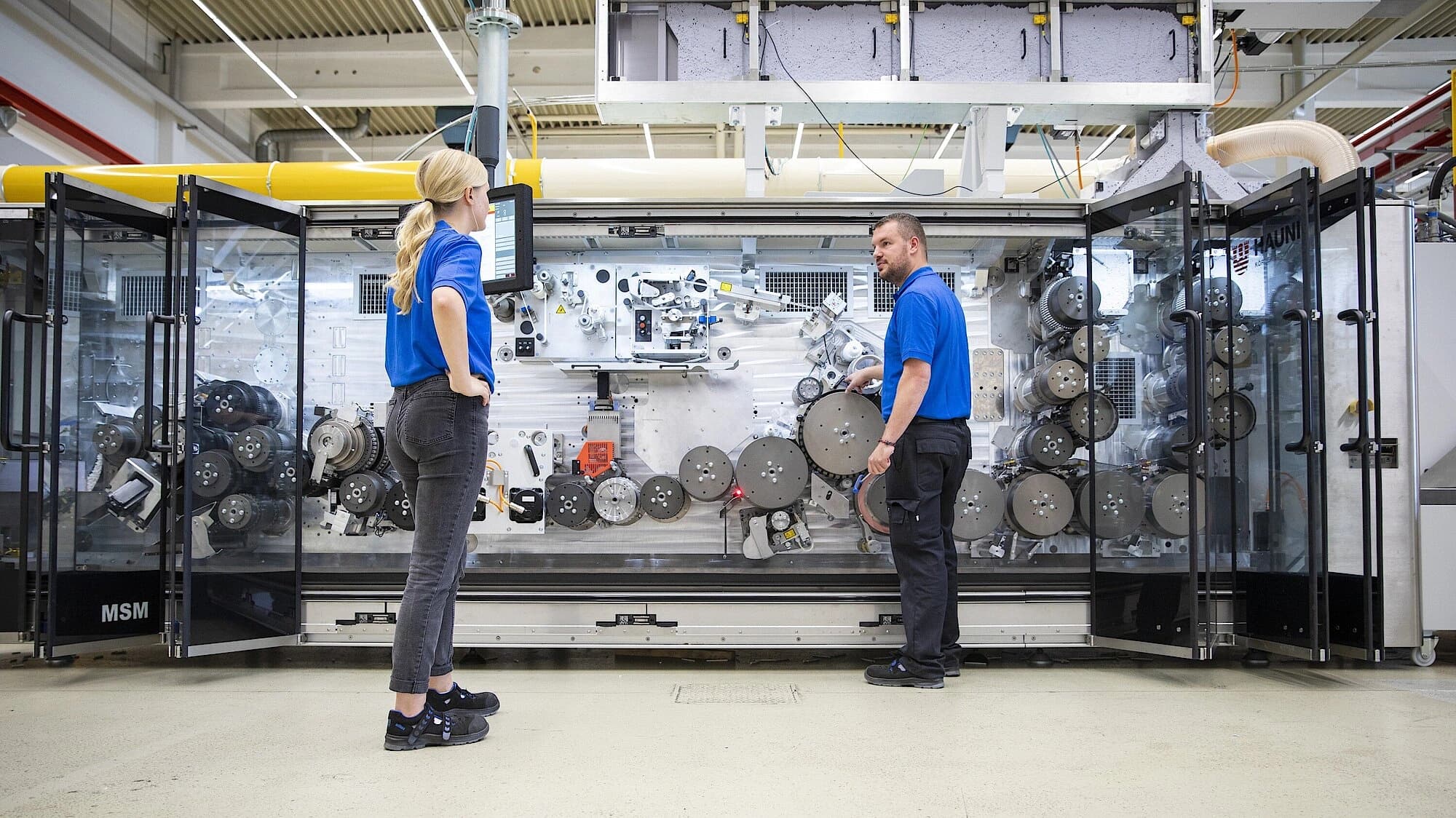 Two Körber employees working on a combining MSM machine