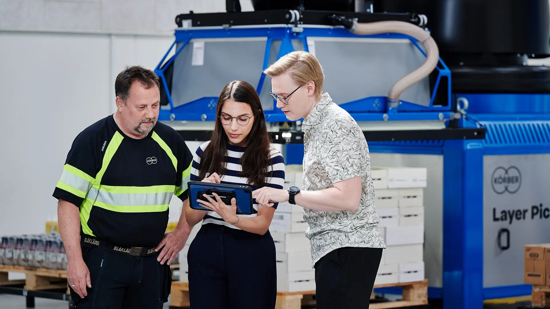 3 Körber employees discussing ideas while they hold a tablet.