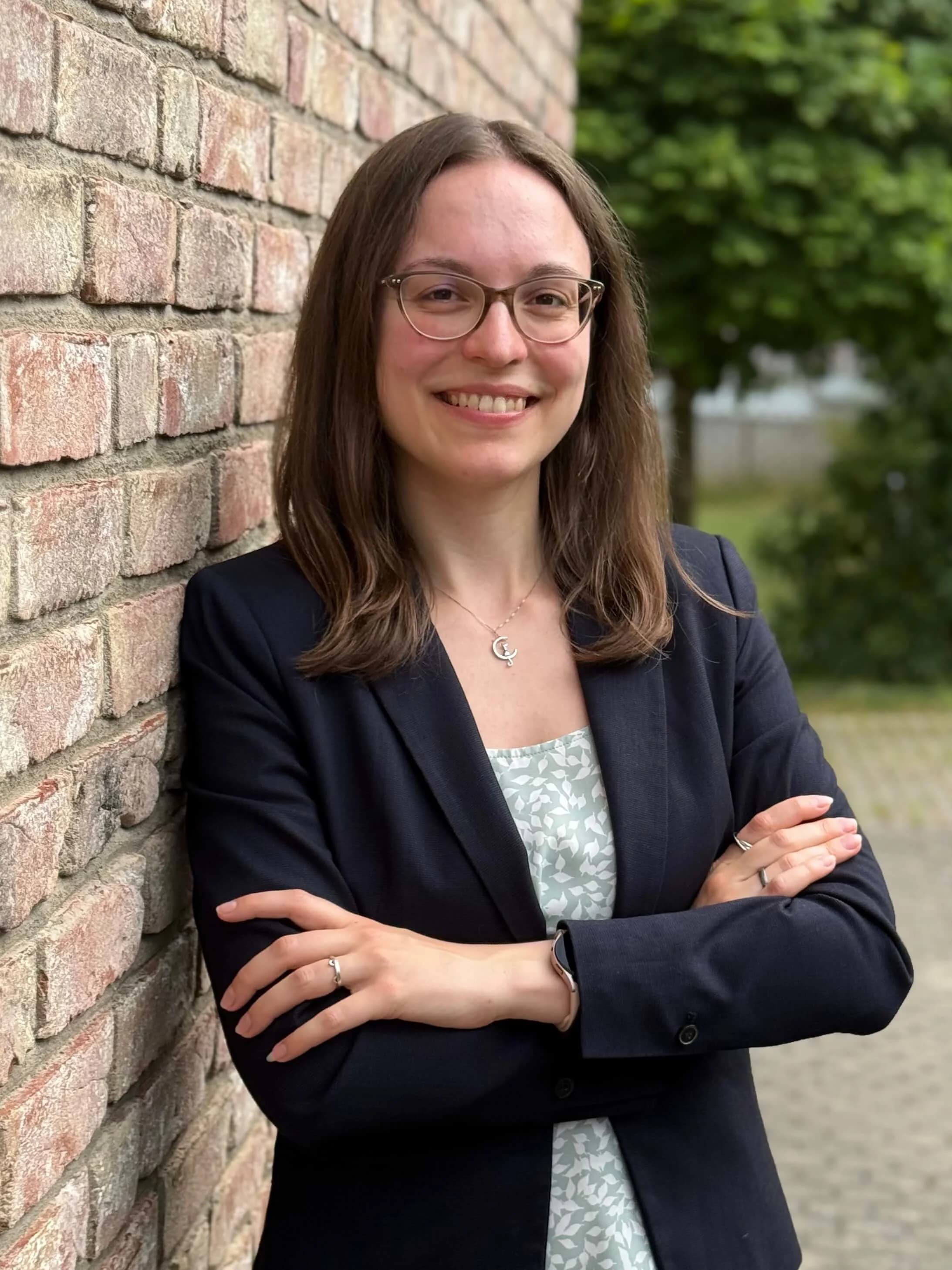 Portrait of Julia Schmitz, Head of Global Software Integration at Körber Business Area Pharma, standing outdoors beside a brick wall.