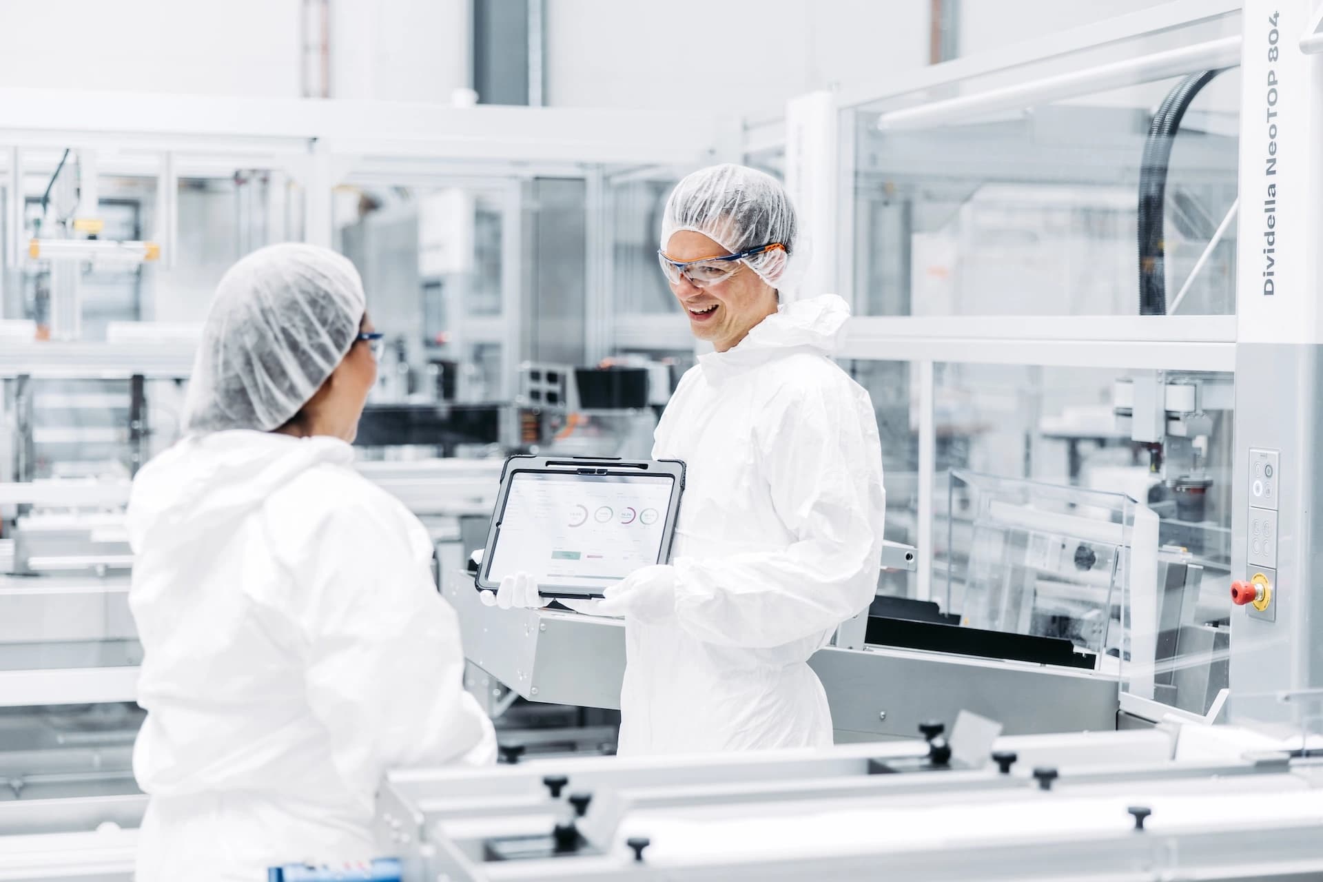 two Körber employees working on pharma performance optimization in a lab environment dressed in safety gear