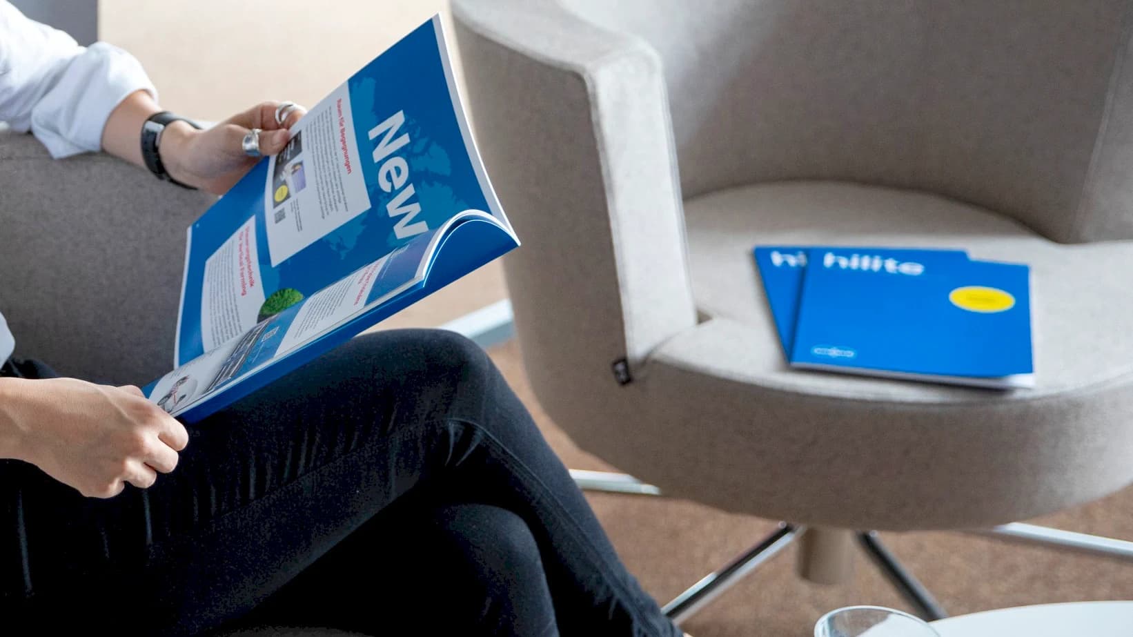 Eine Person sitzt auf einem Stuhl und liest das hilite Magazin.