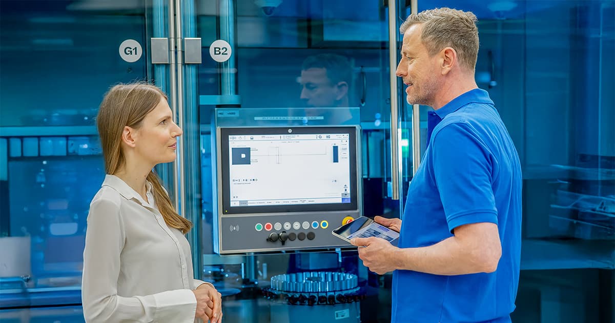 Körber technician and woman standing next to a touchscreen in a pharma facility