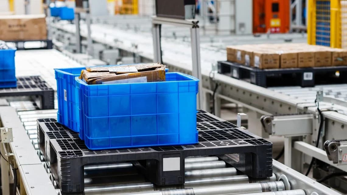 Blue tote moving along an automated conveyor system inside a modern warehouse.