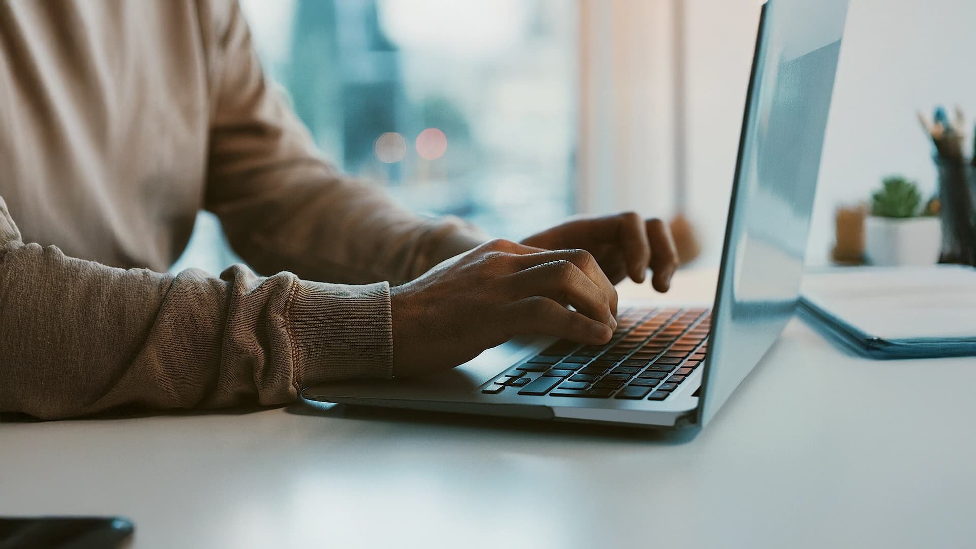 Person, die an einem Laptop-Computer tippt und die Hände über der Tastatur hat.