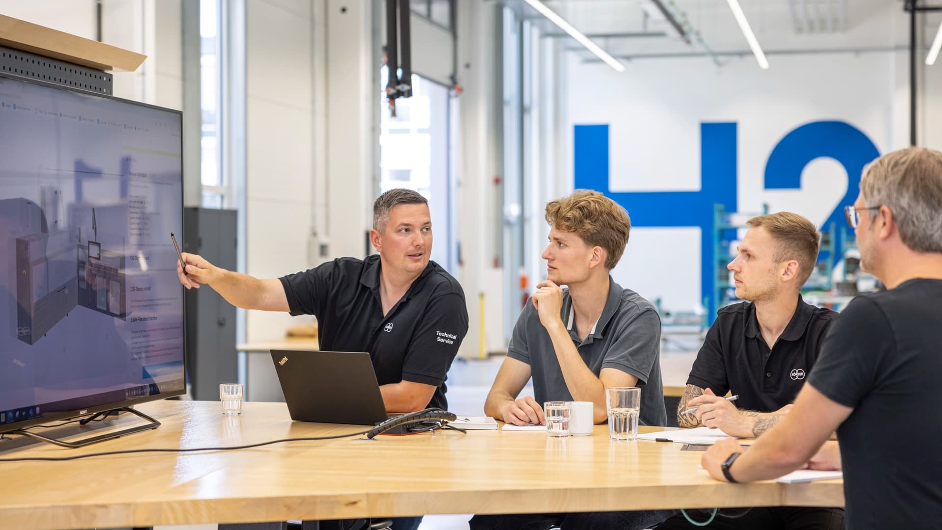 Körber-Mitarbeiter bei einer Besprechung mit Blick auf einen Fernsehbildschirm.