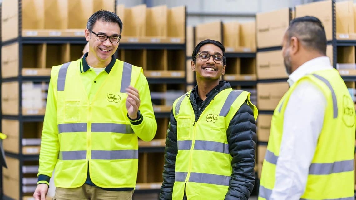 Drei lächelnde und sich unterhaltende Körber-Lagermitarbeiter.