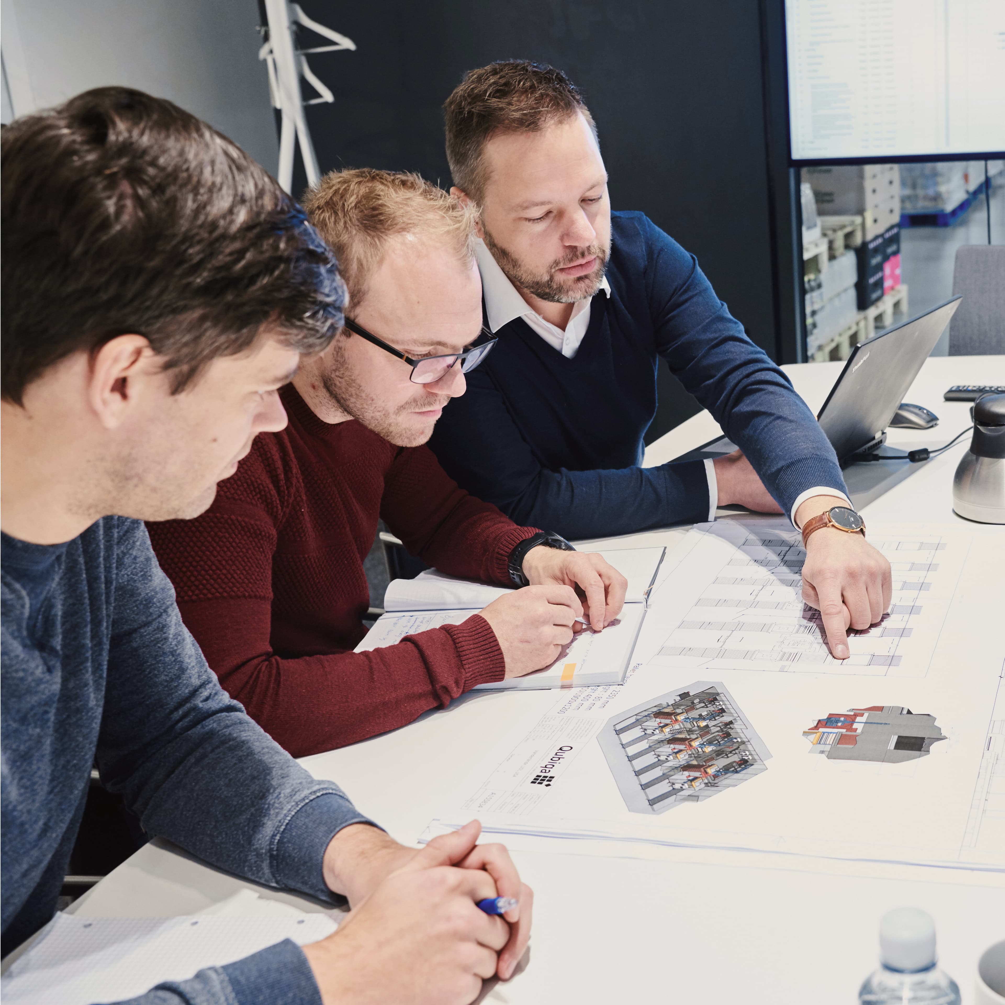 Three men reviewing documents in a meeting