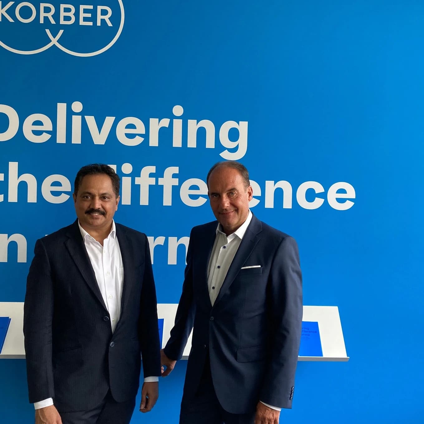 Körber executives standing together in front of a blue Körber-branded wall after announcing the expansion of the company’s pharmaceutical portfolio in India.