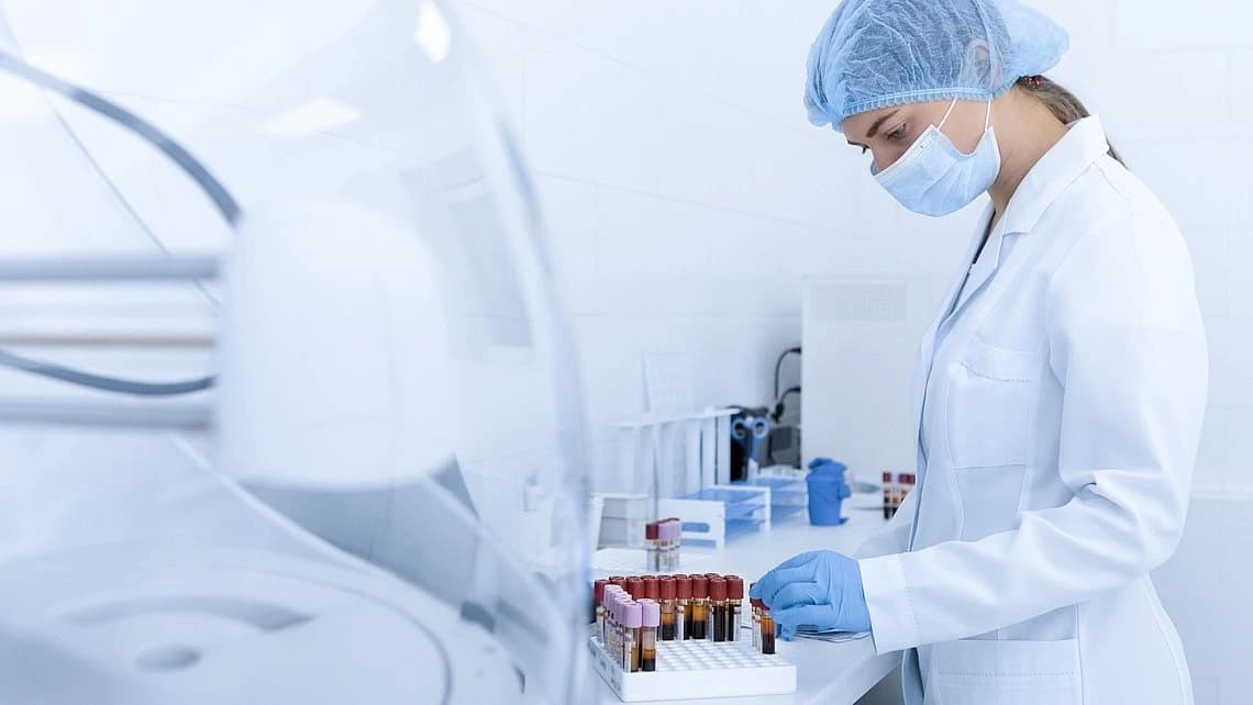 A woman wearing a lab coat in a lab environment is engaged in cell and gene therapy processing.