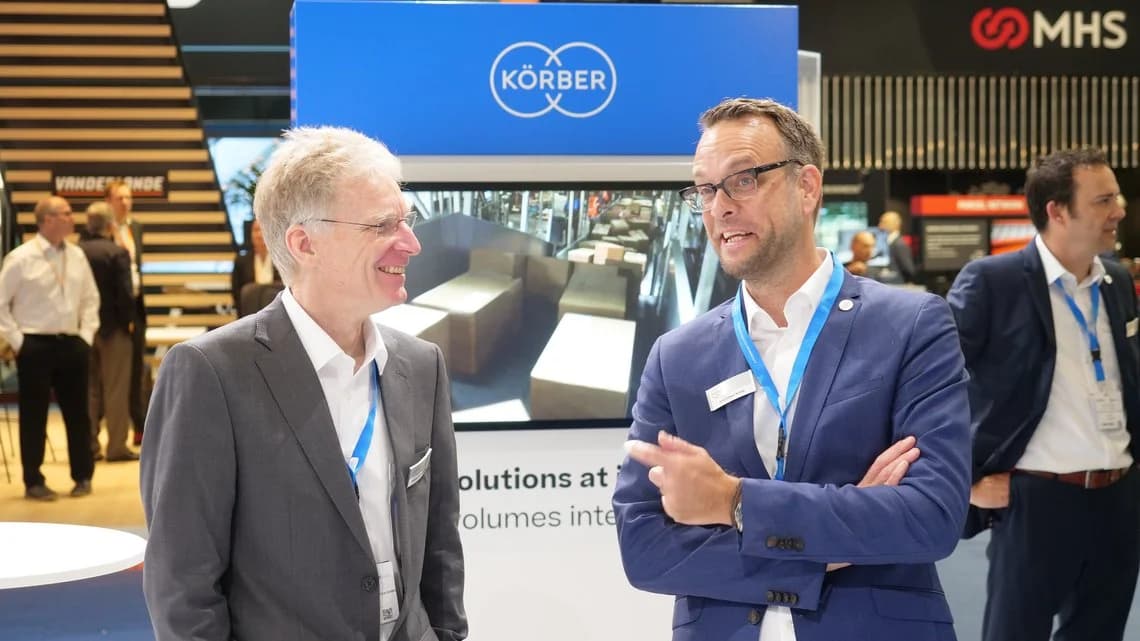 Two Körber employees smiling at talking at Parcel+Post Expo 2022.